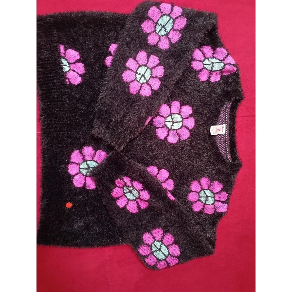 This is a Justice girls' black fuzzy eyelash sweater featuring pink and blue...